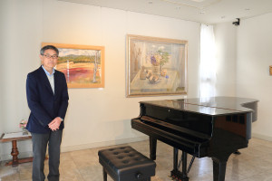 館長の濱崎庄一さんと世良臣絵の油彩画。ピアノがある1階ではコンサートが開かれることも
