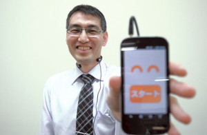 板村英典さん プロジェクトaH理事。関西大学でコミュニケーションを研究後、同団体で笑いの研究について取り組む。手にしているのは笑い声測定システム「アッハ・メーター」