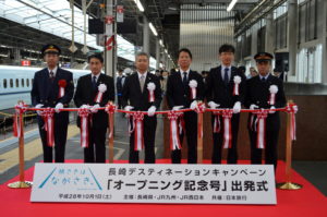 「オープニング記念号」の出発を祝ってテープカットする関係者たち